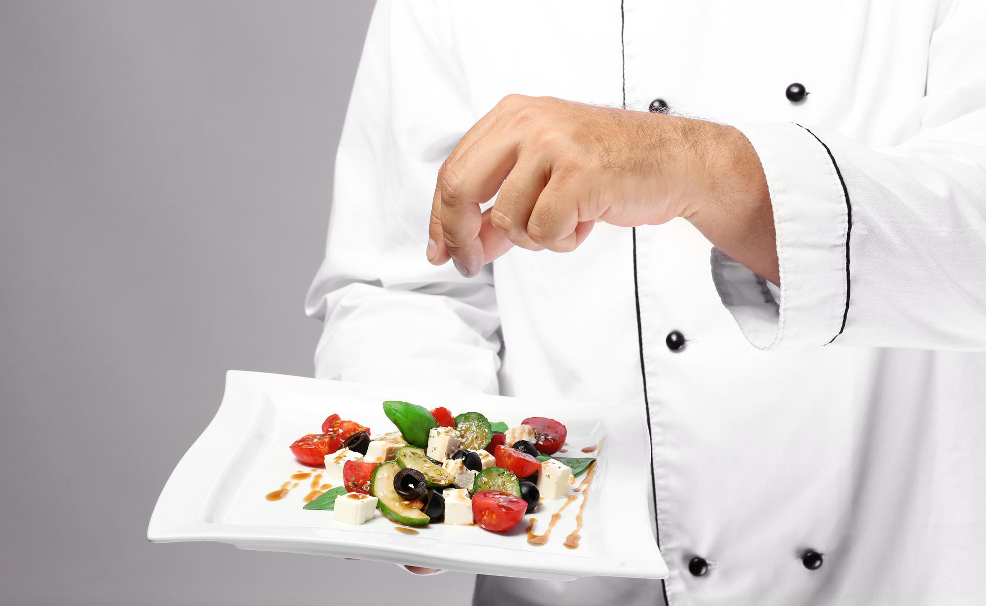 Instructor demonstrating plating technique in kitchen